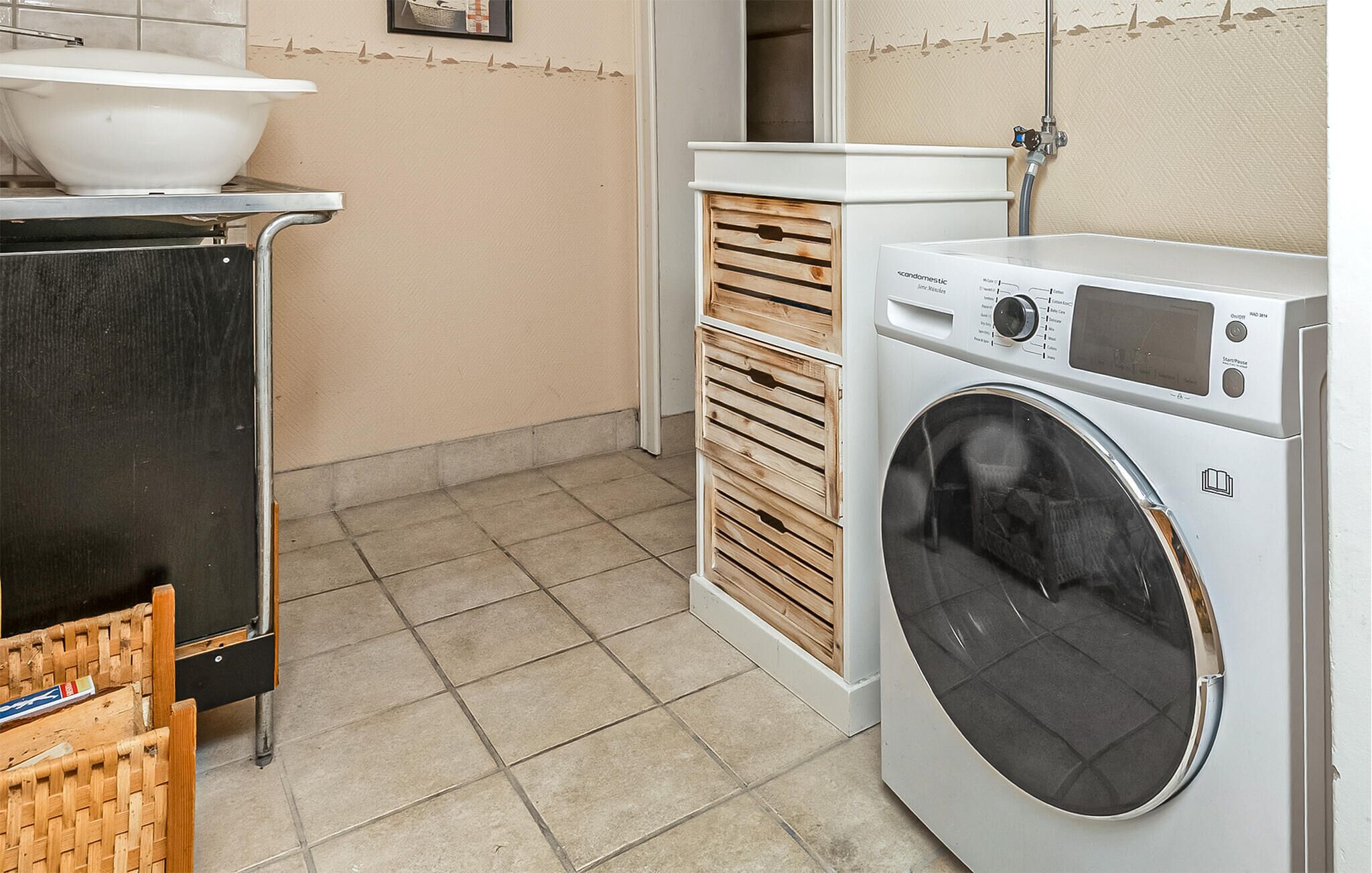 A compact laundry area with a washing machine, a sink, and a drying rack.
