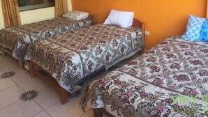 Een kamer met drie bedden, elk voorzien van beddengoed en kussens met een patroon.