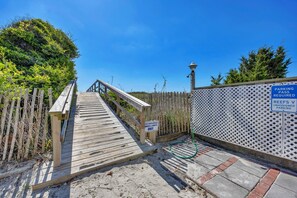 A wooden boardwalk leading to a beach area with a sign indicating 'PARKING PASS REQUIRED' and 'REEFS V UNASSIGNED PARKING.'