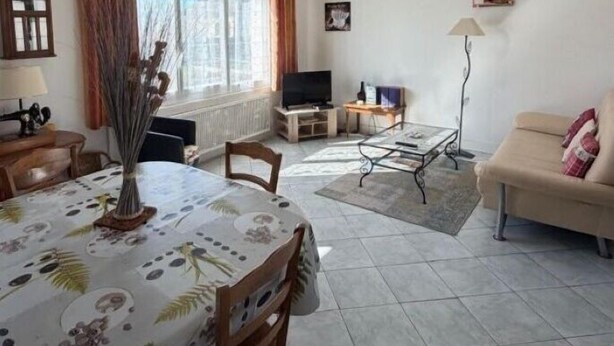 Olohuone, jossa on ruokapöytä, sohva, televisio ja lamppu.
