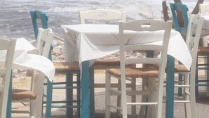 Un espace de restauration en bord de mer, avec des tables et des chaises, offrant une vue sur l’océan.
