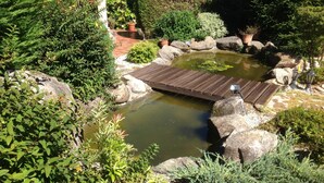 A garden with a wooden bridge over a pond, surrounded by rocks and various plants. - RUSTIC VACATION HOUSE (Mondariz)