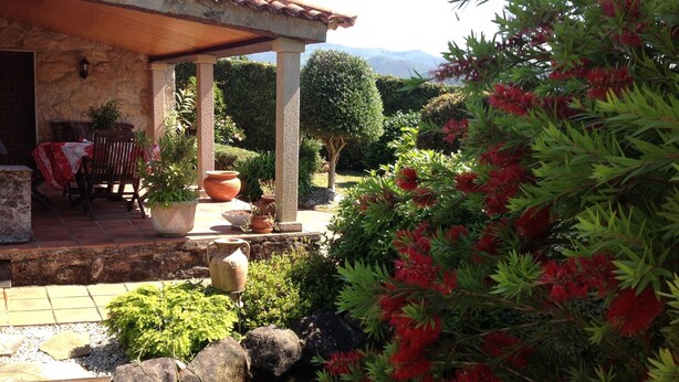 A patio area with a stone table and chairs, surrounded by potted plants and a small water feature. - RUSTIC VACATION HOUSE (Mondariz)