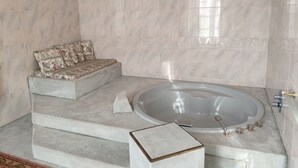 A bathroom with a bathtub, a sofa with floral cushions, and a patterned rug. - Bed and breakfast with hydromassage bath - St Thomas Castle (saint etienne de montluc)