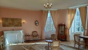 A room with a fireplace, a chandelier, a dining table with chairs, and a large window with curtains. - Bed and breakfast with hydromassage bath - St Thomas Castle (saint etienne de montluc)
