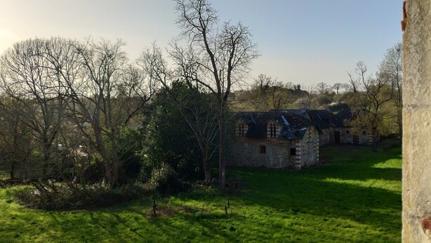 A stone building with a thatched roof, surrounded by a grassy field and trees. - Bed and breakfast with hydromassage bath - St Thomas Castle (saint etienne de montluc)