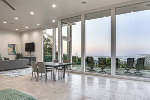 A modern interior with a dining area, large windows, and a view of the sea. - Pool & Coastline Views: Luxe La Jolla Home (La Jolla)