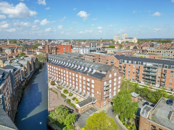 A high-rise building with a river in the foreground, surrounded by other buildings and a clear sky. - Cocoa Suites 37 - York city centre 1 bed apartment with sofa bed (sleeps 3) (York)
