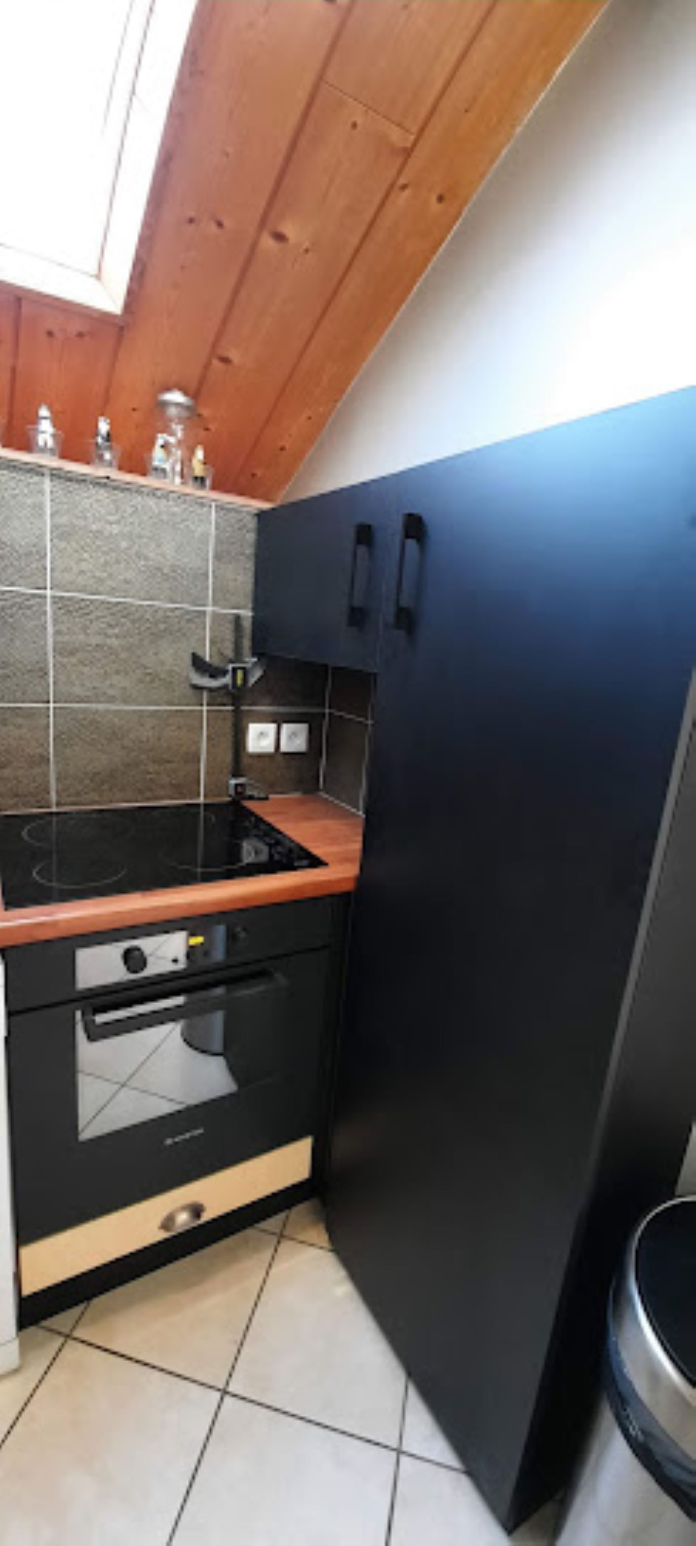 Une cuisine avec un réfrigérateur noir, une cuisinière et un four à micro-ondes.