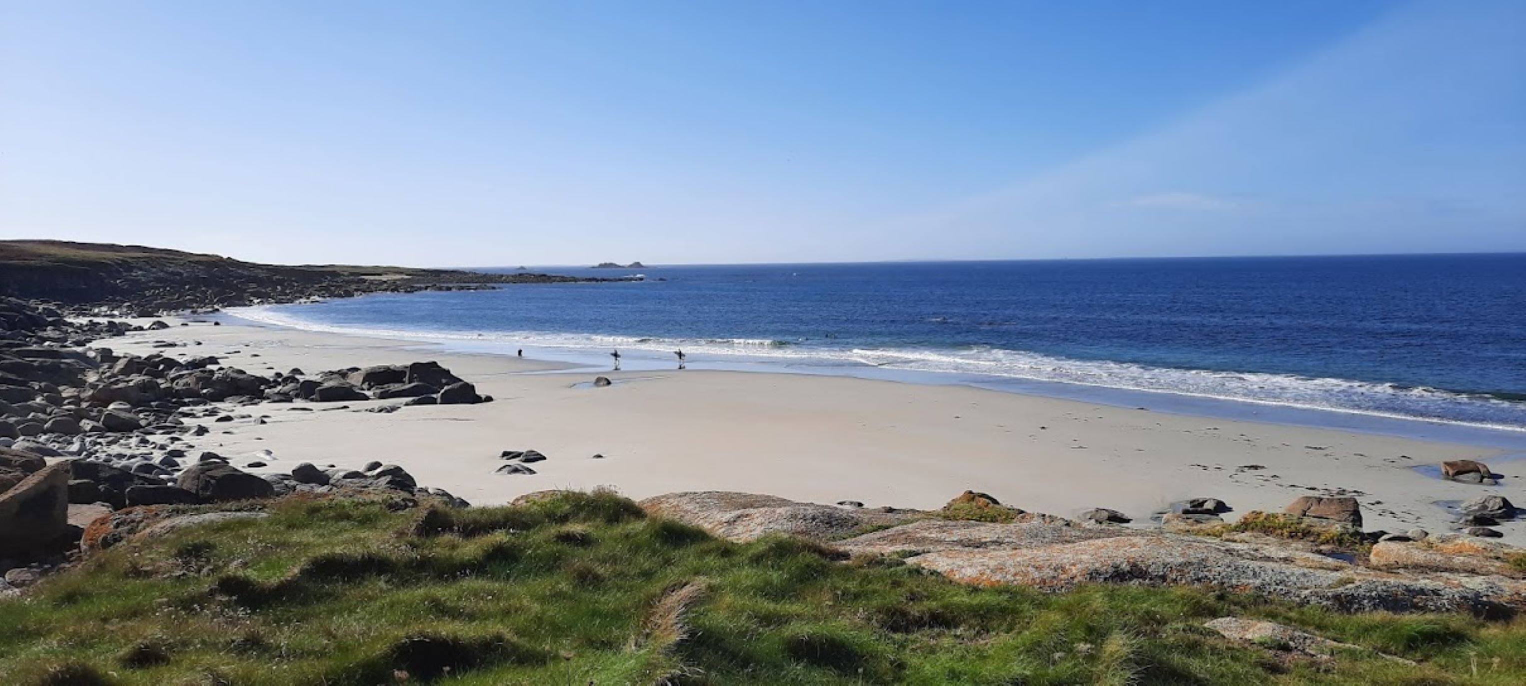 A coastal beach with rocky terrain and a clear view of the ocean.