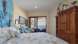A bedroom with a large bed, a wooden wardrobe, and a balcony with a view. - Sonoran Sea E-804 Oceanfront Condo (Puerto Peñasco)