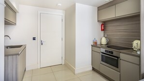 A modern kitchen with a white door, stainless steel appliances, and a wooden backsplash. - Cocoa Suites 35 - York city centre studio (with parking) - sleeps 3 (York)