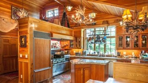 A spacious kitchen with wooden cabinets, a large island, and a chandelier.
