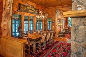 Cozy dining area with a large wooden table and stone fireplace.