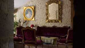 A room with a stone wall, a wooden sofa, two armchairs, a small table, and a mirror with an ornate frame. - Welcome to our house, we are happy to open its doors to you! (Calignac)