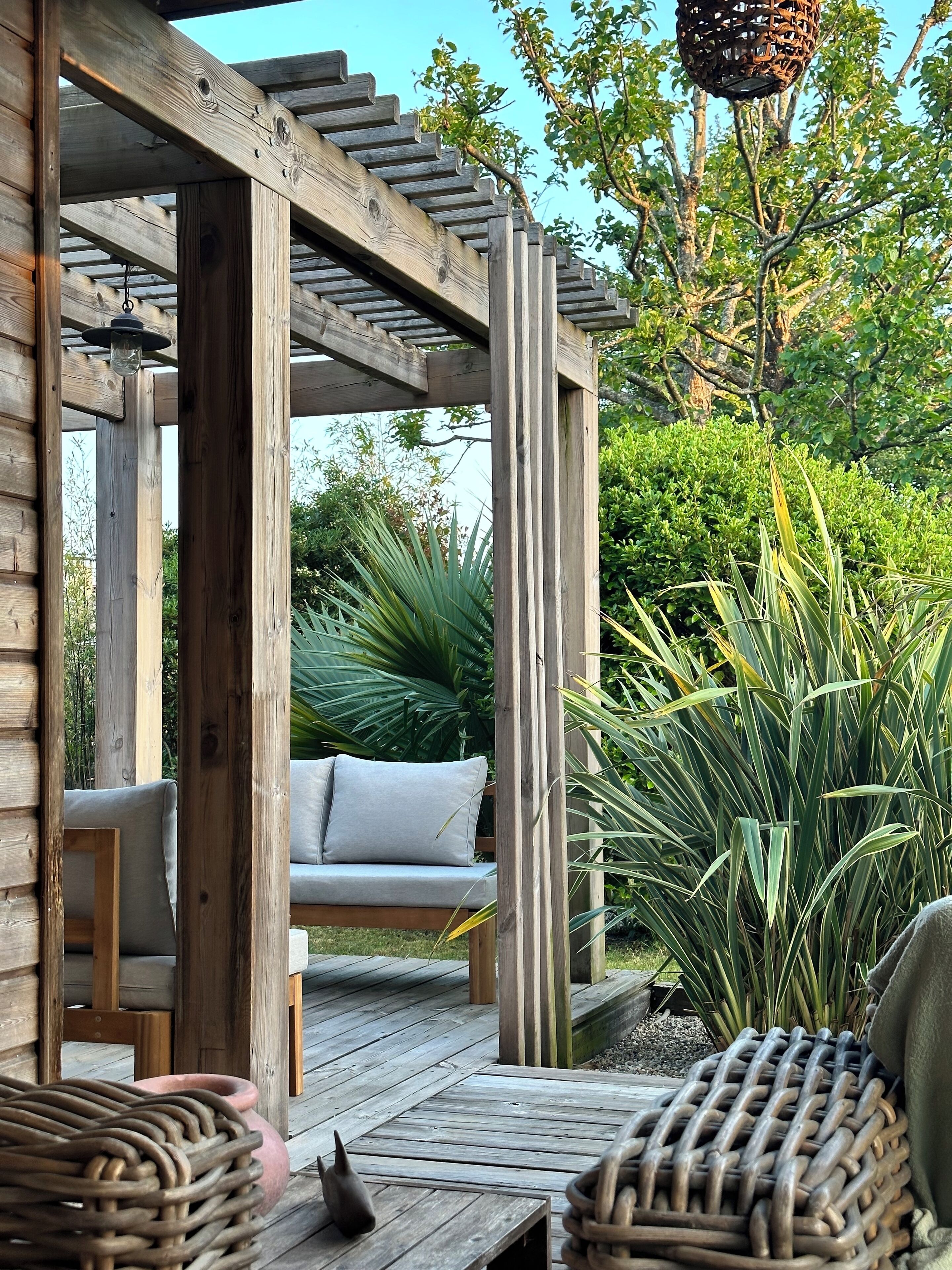 Una pergola in legno con una panca imbottita e un lampadario sospeso.
