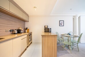 Une cuisine moderne avec un îlot central, un coin repas avec une table ronde et des chaises, et un tableau encadré au mur.