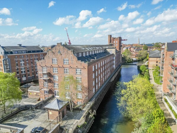 A riverside building with a brick facade, a tower, and a crane in the background.