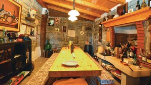 Un comedor rústico con una mesa de madera, paredes de piedra y diferentes botellas y vajillas.