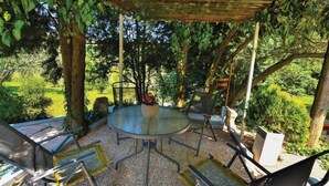 Un espacio al aire libre con una mesa redonda, sillas y una pérgola.