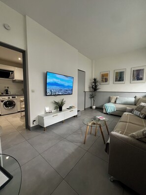 A modern living room with a flat-screen TV mounted on the wall, a sofa, a coffee table, and a small side table.
