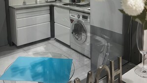 Una cucina moderna con lavatrice, un tavolo in vetro e un ramo di orchidea bianca decorativa.