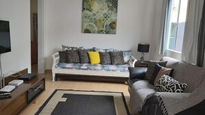 A modern living room with a sofa, a coffee table, and a TV. - Vacation Home in Arraial do Cabo (Praia Grande)