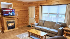 Una sala de estar acogedora con chimenea, un sofá, una mesita de centro y un televisor.