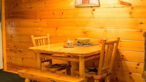 Una mesa de madera con cuatro sillas, un banco y un pequeño adorno sobre la mesa.