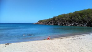 A beach with clear blue water, sandy shore, and rocky cliffs. - ---- LOVE DESHAIES 2 --- (DESHAIES)