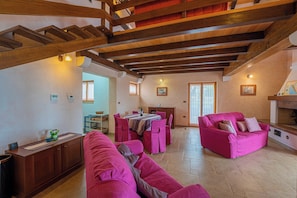 Ein geräumiger Wohnbereich mit Holzboden, einem Esstisch mit Stühlen und einem rosa Sofa.