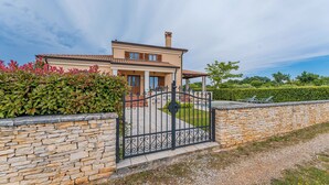 Una casa de dos pisos con un muro de piedra y una reja negra de hierro forjado.