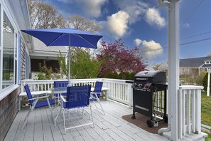 A covered patio with blue chairs and a grill.
