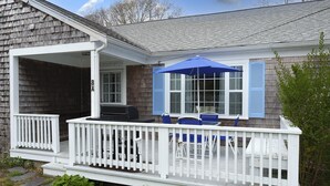 Uma casa com varanda, churrasqueira e um guarda-sol azul.