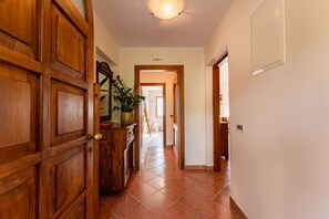 A hallway with wooden doors, a potted plant, and a tiled floor leading to a bathroom.