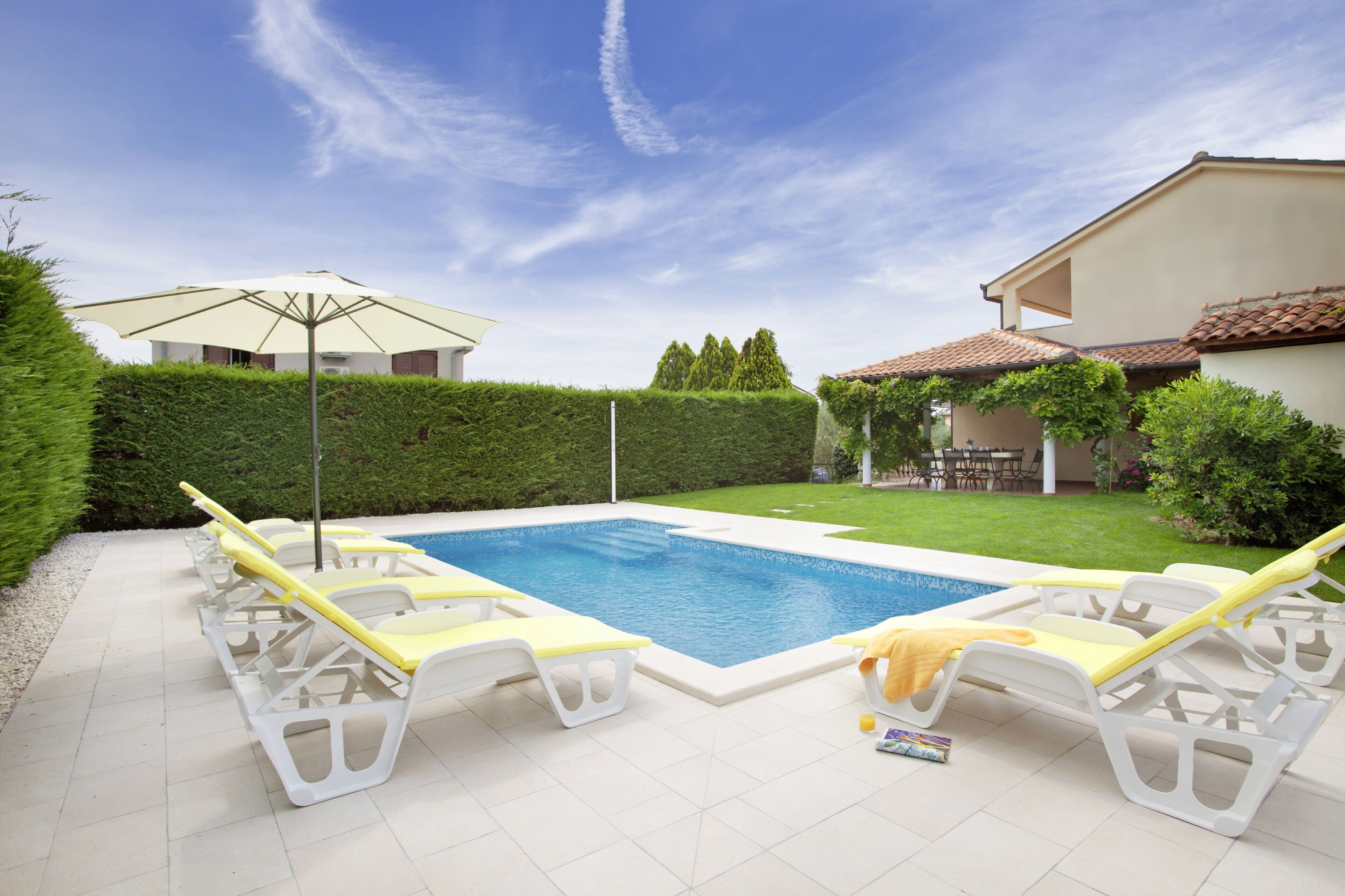 A swimming pool with lounge chairs and an umbrella.