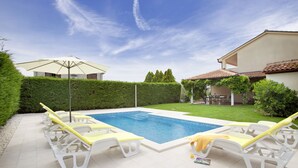 Una piscina con sillas de descanso y una sombrilla.