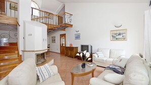 Un salón espacioso con chimenea, una escalera y un comedor.