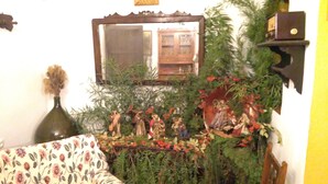 A room with a mirror, a floral sofa, and a small statue of religious figures. - Cortijo la Colá - Cañete la Real, Malaga (Cañete la Real)