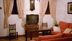 A living room with a wooden table, two chairs, a sofa, and a television. - Cortijo la Colá - Cañete la Real, Malaga (Cañete la Real)