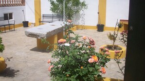A courtyard with a stone bench, potted plants, and a view of the countryside. - Cortijo la Colá - Cañete la Real, Malaga (Cañete la Real)