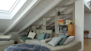 Une pièce de style loft avec un plafond haut, un canapé, un fauteuil et une bibliothèque.