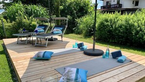 Une terrasse en bois avec des chaises longues, des tapis de yoga et des bougies.