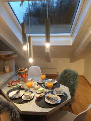 A dining area with a table set for breakfast, including plates, cutlery, and a variety of food items. - Chiemgau loft between mountain experience and lake magic - balcony and garden (Riedering)