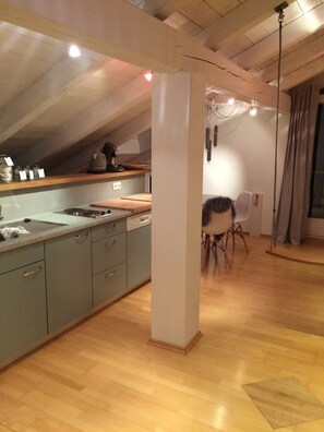 Enjoy meals in the spacious kitchen with a central island, sink, and stove, adjacent to a dining area with a table and chair.