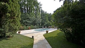 Ein Garten mit Swimmingpool, Kiesweg und Liegestühlen.