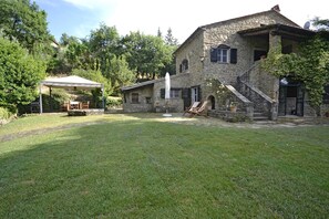 A stone house with a covered patio, outdoor seating, and a grassy yard. - Villa in Il Castagno with 3 bedrooms sleeps 7 (Il Castagno)