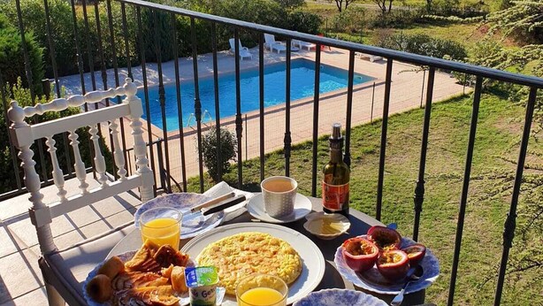 A balcony with a table set for breakfast overlooking a swimming pool and a mountainous landscape. - Beautifull villa, 3,360 sq.m garden; only 1 km away from the Saint-Endréol golf club (La Motte)