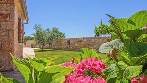 Un bâtiment en pierre, doté d’un mur en pierre et d’une pelouse verdoyante.