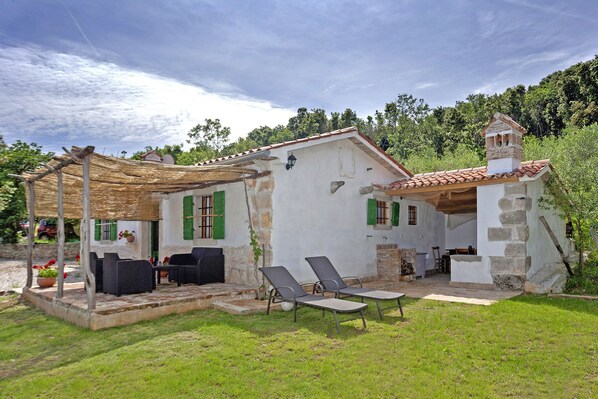 Une maison de campagne dotée d’un patio aménagé avec du mobilier d’extérieur et une cheminée en pierre.